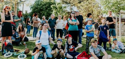 A diverse group of people enjoying a sunny day at an outdoor community event in a park setting.