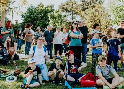 A diverse group of people enjoying a sunny day at an outdoor community event in a park setting.