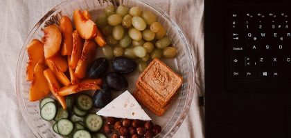 A delightful snack plate with fruits, cheese, and a laptop for a healthy lifestyle.