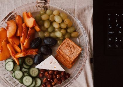 A delightful snack plate with fruits, cheese, and a laptop for a healthy lifestyle.